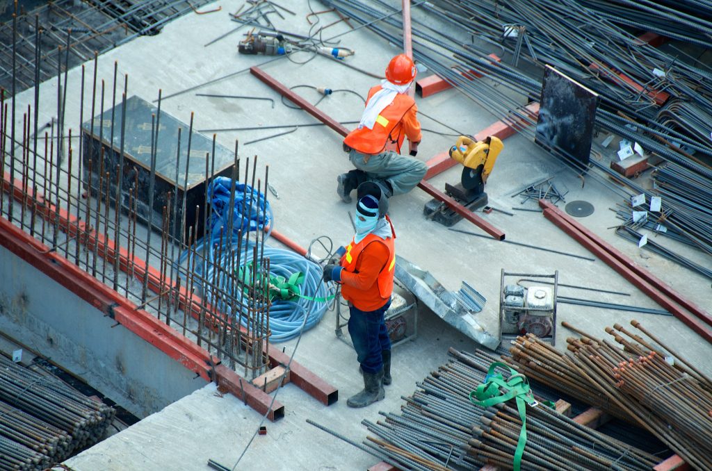 Deux ouvriers en tenue de travaux sur une surface en construction